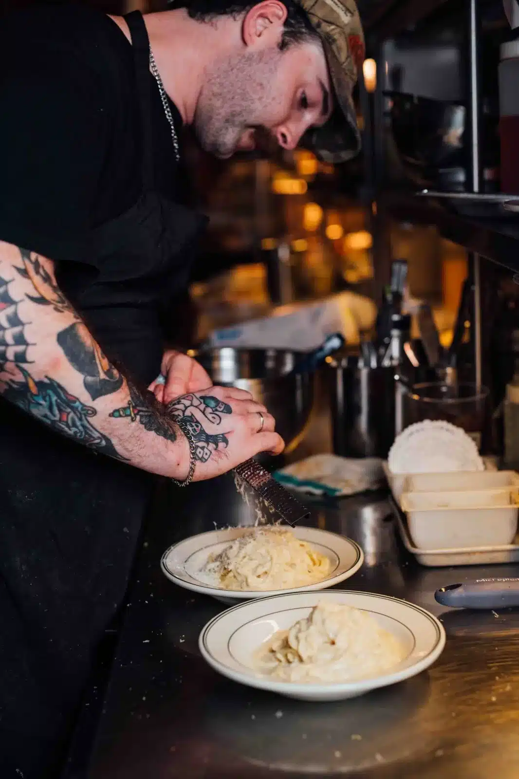 Le chef râpe du parmesan sur un cacio e pepe