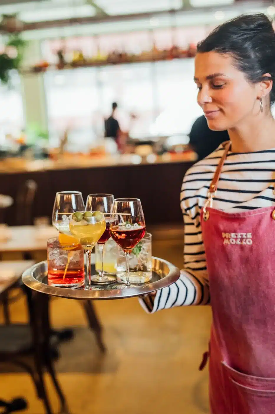 Serveuse avec un plateau de cocktails au bar de Prezze Mollo